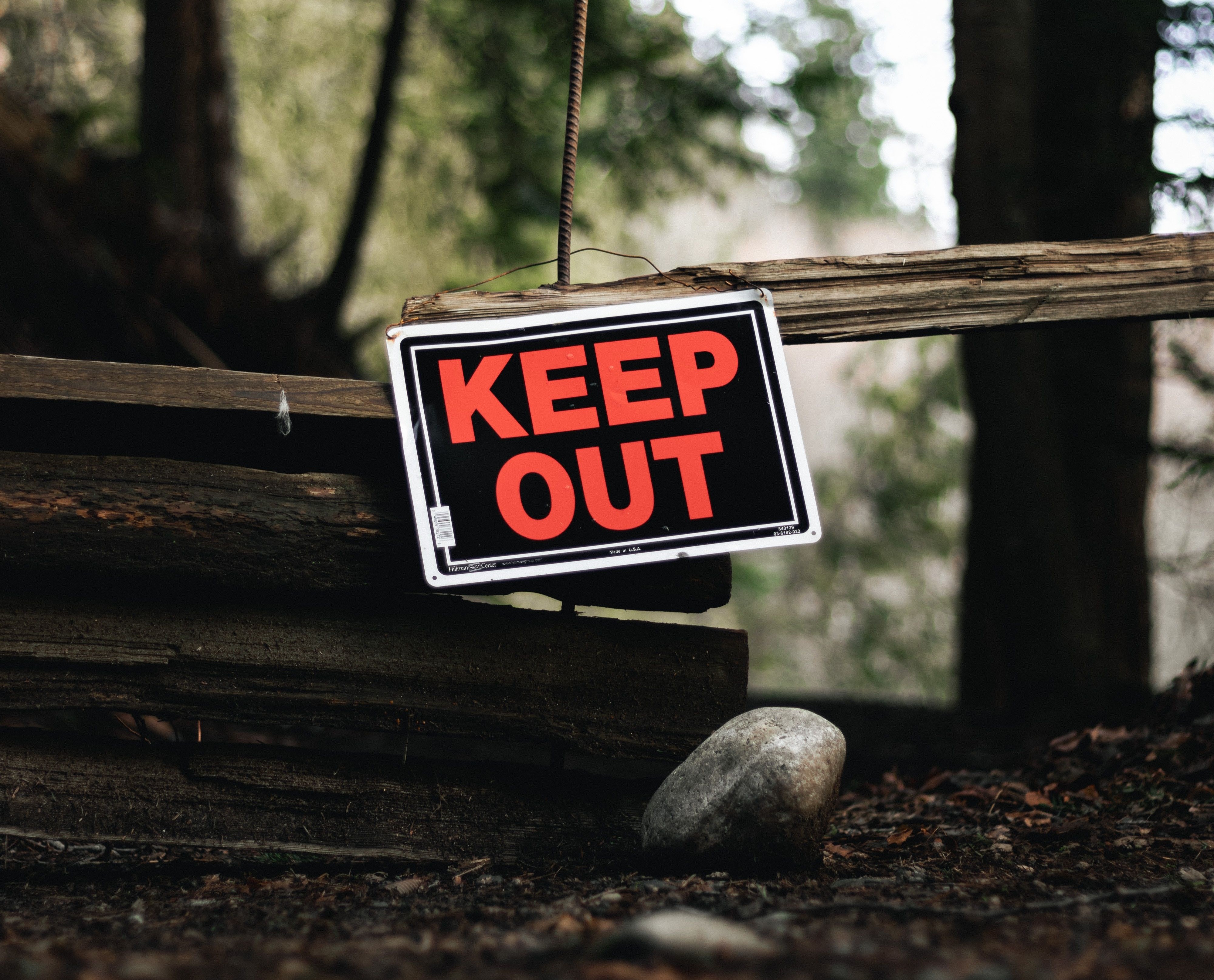 A KEEP OUT sign on a worn wooden fence — old patterns guard what feels safe